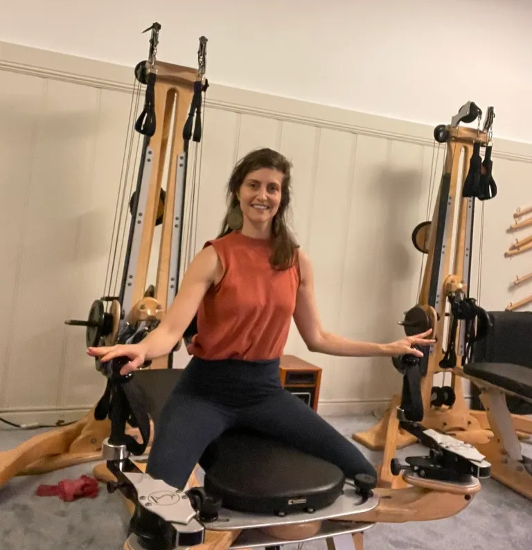 Stephanie Ciancio seated at a GYROTONIC® Pulley Tower, hands on the handle unit