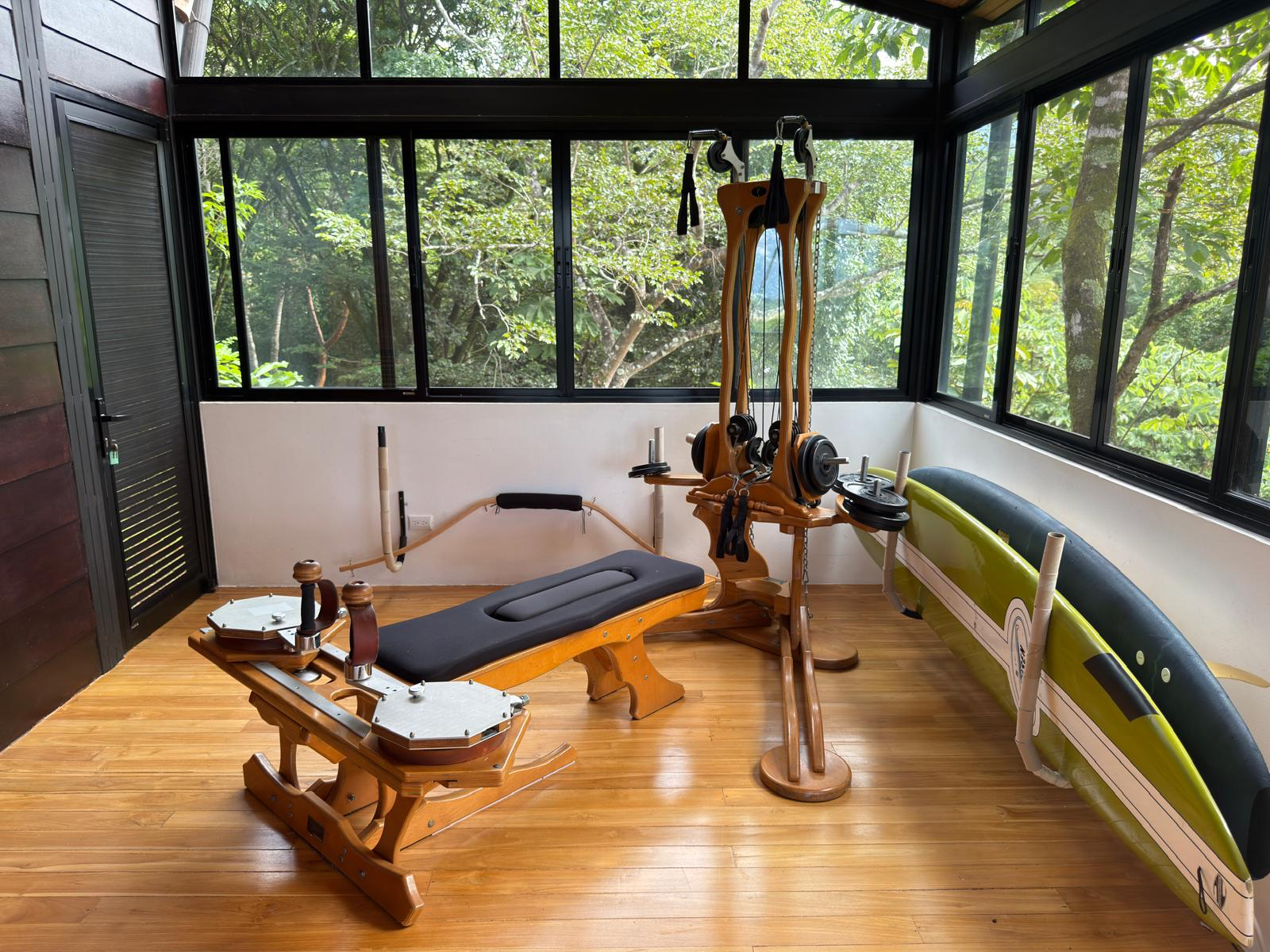 The GYROTONIC® Pulley Tower in a glass-walled studio looking out into the forest canopy